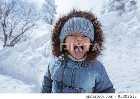 kid enjoying lollipop outside during snowy winter 93002618