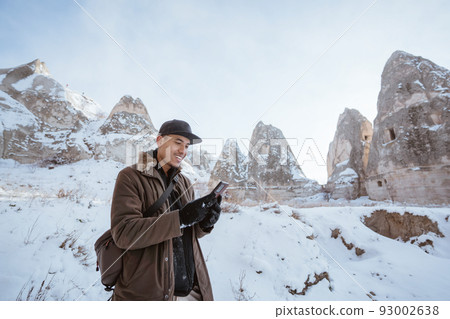 man using phone outside at valley in cappadocia man using phone outside at valley in cappadocia 93002638