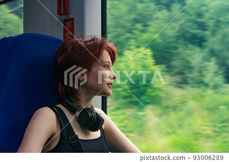 girl rides a train outside the city and looks out the window at a natural landscape blurred in motion 93006289