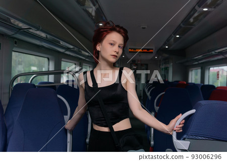 beautiful young red-haired woman posing in a commuter train car 93006296