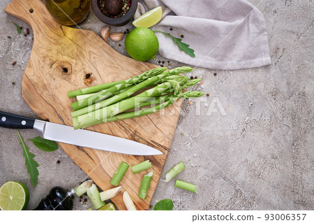 Green organic natural Asparagus on wooden cutting board at kitchen table Green organic natural Asparagus on wooden cutting board at kitchen table 93006357