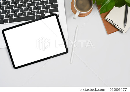 Top view digital tablet with blank display, laptop, coffee cup and notebooks on white table 93006477