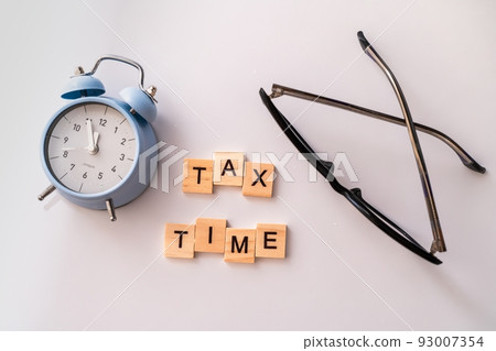 Close-up of alarm clock next to tax time concept on chalkboard 93007354