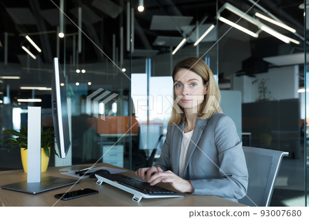 Portrait of a sensible and fair successful woman, businesswoman working in a modern office, at the computer, confident and focused 93007680