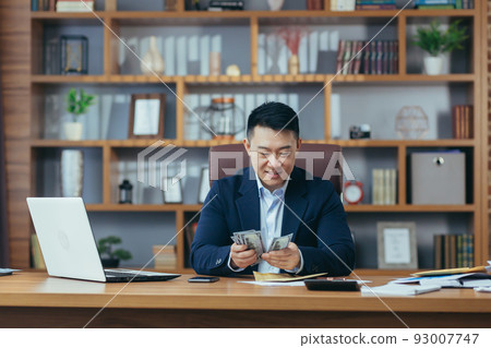 Satisfied young man asian office worker received money, salary, cash reward in an envelope, counts Satisfied young man asian office worker received money, salary, cash reward in an envelope, counts 93007747