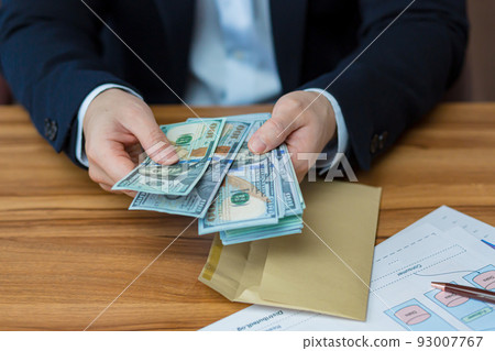 Close up photo hands of young businessman man holds and opens envelope with money, dollars, currency, holds in hands at table, shows, counts Close up photo hands of young businessman man holds and opens envelope with money, dollars, currency, holds in hands at table, shows, counts 93007767