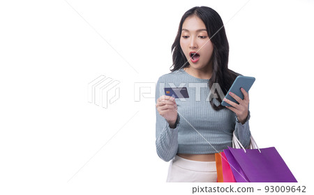 Excited smile Asian woman looking mobile phone holding shopping bag show credit card payment Excited smile Asian woman looking mobile phone holding shopping bag show credit card payment 93009642