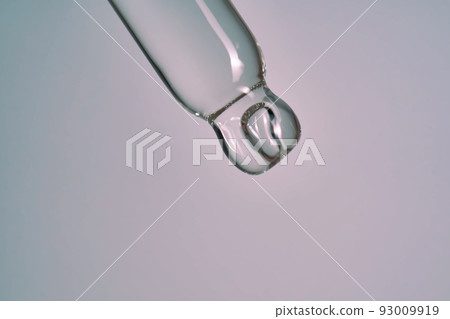 serum pipette close-up with falling drop on purple background 93009919