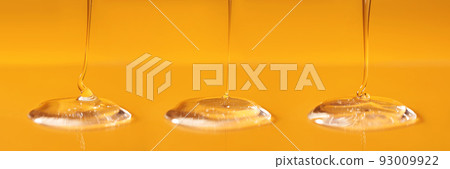 Three drops of body gel or shampoo pouring from above on a yellow saturated background. Banner. 93009922