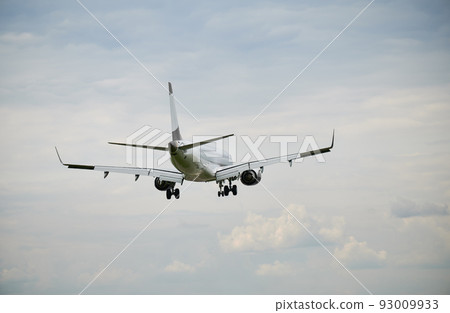 Back view of commercial airplane flying in the sky at cloudy weather. Travel concept. 93009933
