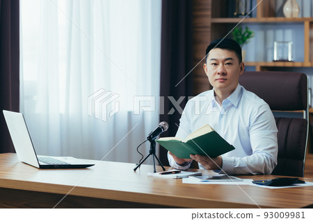 Asian freelancer records audio podcasts, businessman works in office, uses professional microphone and laptop 93009981