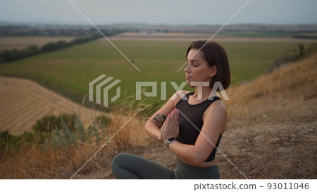 Calm serene sporty young woman meditate while sitting in namaste pose with eyes closed 93011046