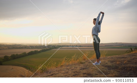 Caucasian female runner standing and warming up in preparation for a jogging run Caucasian female runner standing and warming up in preparation for a jogging run 93011053