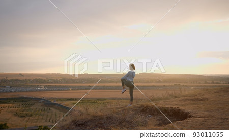 Female runner warming-up her legs on a high mountain during the sunset Female runner warming-up her legs on a high mountain during the sunset 93011055