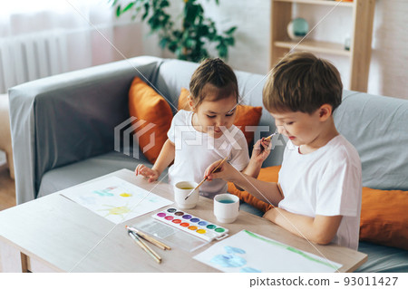 Children paint nature on sheets while sitting at the table 93011427