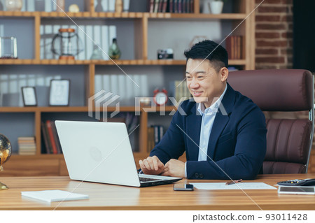 Young handsome asian man, businessman, lawyer, director talking on a video call from a laptop in the office, holds a meeting, consultation, discussion 93011428