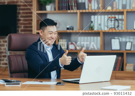 Young handsome asian man, businessman, lawyer, director talking on a video call from a laptop in the office, holds a meeting, consultation, discussion Young handsome asian man, businessman, lawyer, director talking on a video call from a laptop in the office, holds a meeting, consultation, discussion 93011432