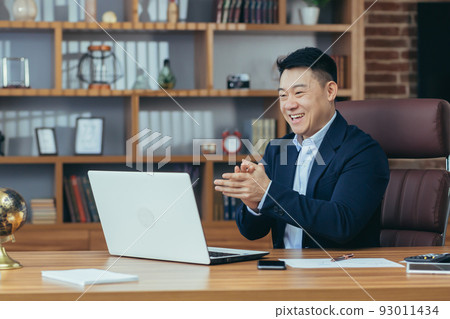 Young handsome asian man, businessman, lawyer, director talking on a video call from a laptop in the office, holds a meeting, consultation, discussion Young handsome asian man, businessman, lawyer, director talking on a video call from a laptop in the office, holds a meeting, consultation, discussion 93011434