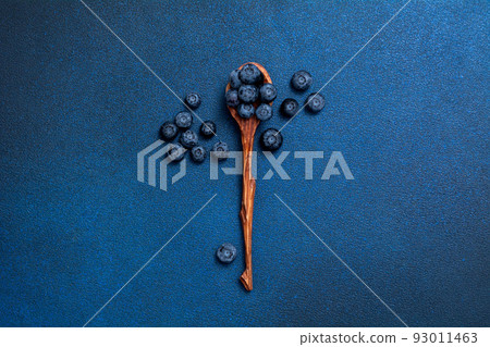 Fresh blueberries in a wooden spoon. Berries on a blue background. View from above. 93011463
