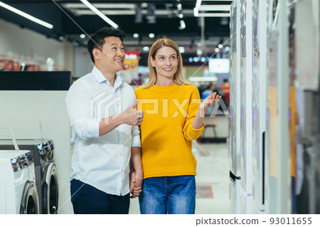happy asian couple family man and woman make a choice choose of new household home appliances in supermarket survey Refrigerator Fridge cooler, freezer, cold store purchase and shopping 93011655