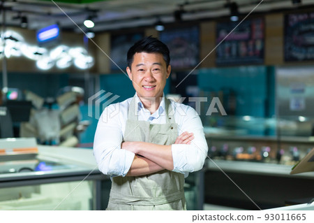 Portrait of Asian salesman in seafood and fish shop man smiling with arms crossed and looking at camera Portrait of Asian salesman in seafood and fish shop man smiling with arms crossed and looking at camera 93011665