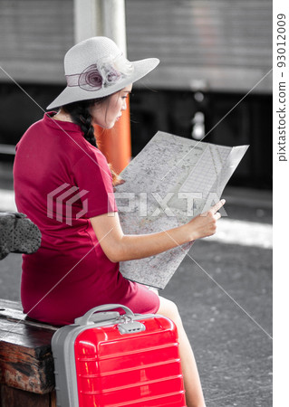 Asian woman pregnant in red dress carrying red luggage and look at the map at railway station travel,traveler with backpack in summer Holiday concept Thailand 93012009