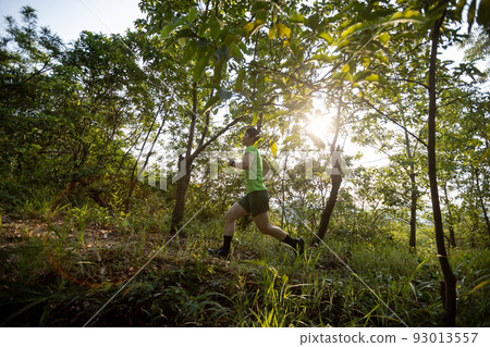 Woman trail runner running at sunrise tropical forest mountain peak 93013557