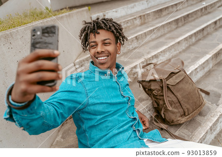 Guy taking selfie on smartphone sitting on steps Guy taking selfie on smartphone sitting on steps 93013859