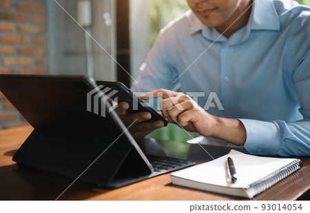 Send a message to a colleague, a businessman, confident in matching a tablet and sitting in office. 93014054