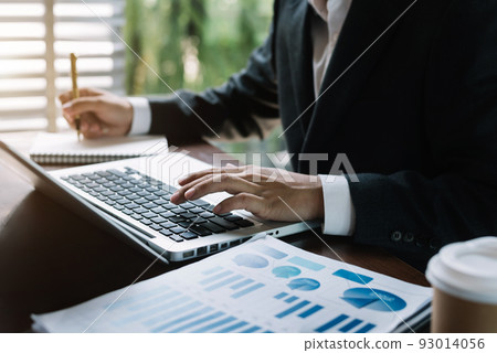 Male businessman use a laptop computer and take notes in the notebook at the office desk in the morning. 93014056