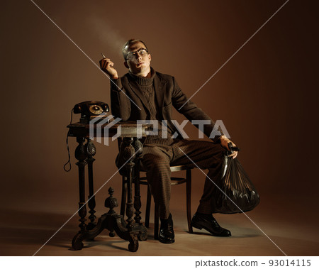 Retro style portrait of young man, writer and traveler wearing vintage style clothes isolated over dark brown background. Business, art, fashion concept Retro style portrait of young man, writer and traveler wearing vintage style clothes isolated over dark brown background. Business, art, fashion concept 93014115