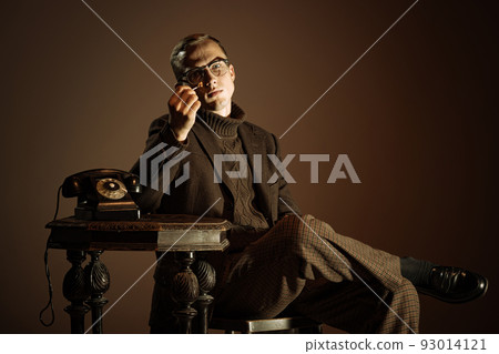 Retro style portrait of young man, writer and traveler wearing vintage style clothes isolated over dark brown background. Business, art, fashion concept Retro style portrait of young man, writer and traveler wearing vintage style clothes isolated over dark brown background. Business, art, fashion concept 93014121