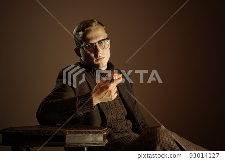 Retro style portrait of young man, writer and traveler wearing vintage style clothes isolated over dark brown background. Business, art, fashion concept 93014127