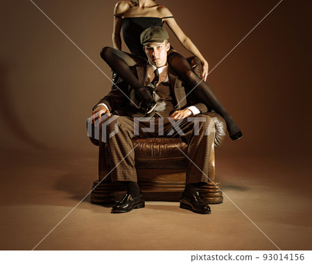 Vintage style portrait of man and woman in 1920s style fashion outfits isolated over dark brown background. Relationship, business, love, art, fashion Vintage style portrait of man and woman in 1920s style fashion outfits isolated over dark brown background. Relationship, business, love, art, fashion 93014156