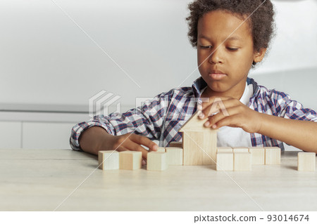 Little boy raises his hand to the house from wooden cubes Little boy raises his hand to the house from wooden cubes 93014674