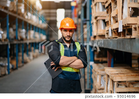 Male factory manager using digital tablet in warehouse shelf looking at camera.Products and corrugated cardboard.looking at camera. 93014696