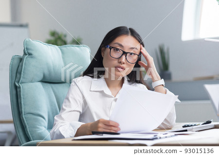Frustrated and upset asian business woman working in office, holding documents with bad and negative financial indicators of company, financier working. Frustrated and upset asian business woman working in office, holding documents with bad and negative financial indicators of company, financier working. 93015136