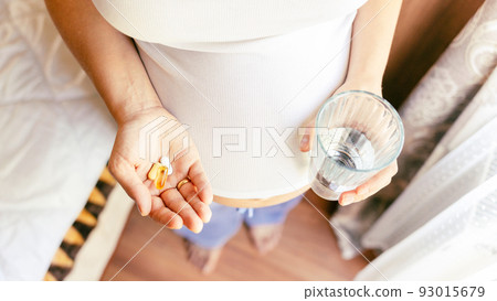 Healthcare, treatment, supplements. Happy smiling woman taking pill with supplement vitamin Omega 3. Pregnancy, medicine health care concept. Healthcare, treatment, supplements. Happy smiling woman taking pill with supplement vitamin Omega 3. Pregnancy, medicine health care concept. 93015679