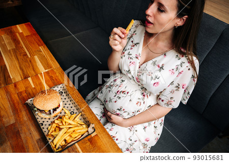 Pregnant woman hamburger eat. Hungry pretty pregnancy female eating tasty burger. Fast food, people and unhealthy eating concept. Pregnant woman hamburger eat. Hungry pretty pregnancy female eating tasty burger. Fast food, people and unhealthy eating concept. 93015681