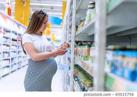 Infant formula woman shopping. Young pregnant woman buying infant baby formula milk on supermarket background. Healthy baby formula concept. Infant formula woman shopping. Young pregnant woman buying infant baby formula milk on supermarket background. Healthy baby formula concept. 93015756