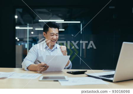 Successful and confident asian businessman reading bank letter and financial report, happy and celebrating triumph success, holding hand up 93016098