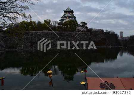 Osaka Prefecture, Japan, Osaka Castle in spring, cherry blossoms in full bloom and a splendid castle tower, houseboats moored in the moat 93017375