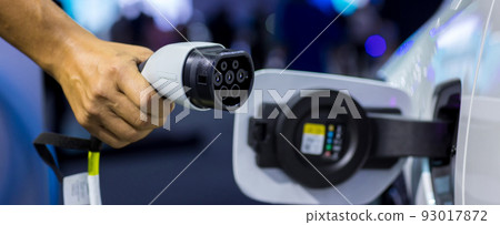 Hand holding Electric car charger. Electric Vehicle EV Charging station and Charger. 93017872