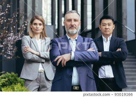 Portrait of serious diverse business team, employees with boss together looking at camera seriously and thoughtfully, group of business people outside office in business suits Portrait of serious diverse business team, employees with boss together looking at camera seriously and thoughtfully, group of business people outside office in business suits 93019166