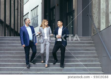 Diverse business team man and woman walking together on stairs outside office building, business people take a walk on break and have fun talking Diverse business team man and woman walking together on stairs outside office building, business people take a walk on break and have fun talking 93019168