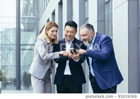 Diverse business team, men and women outside office smiling and happy, watching funny content on phone 93019169