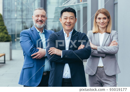 Business team, male and female colleagues in business attire looking at camera and smiling with arms crossed Business team, male and female colleagues in business attire looking at camera and smiling with arms crossed 93019177
