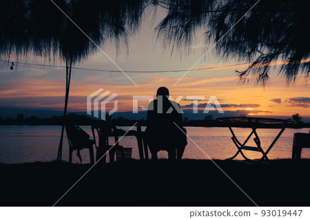 Silhouette of a man enjoying the sunset view by the riverside in Kampot, Cambodia Silhouette of a man enjoying the sunset view by the riverside in Kampot, Cambodia 93019447