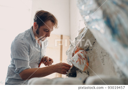 Workplace mosaics master making smalt glass mosaic panel. Man mosaicist at work 93019457