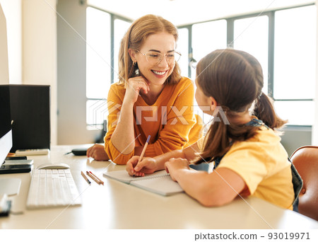 Cheerful mother doing homework with daughter at home 93019971